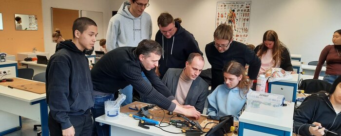 Schülerinnen und Schüler mit betreundenen Personen beim Experimentieren im Klassenzimmer