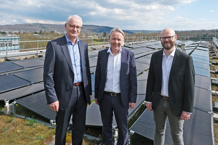 Drei Männer stehen neben einer Photovoltaik-Anlage auf dem Dach der Hochschule Koblenz