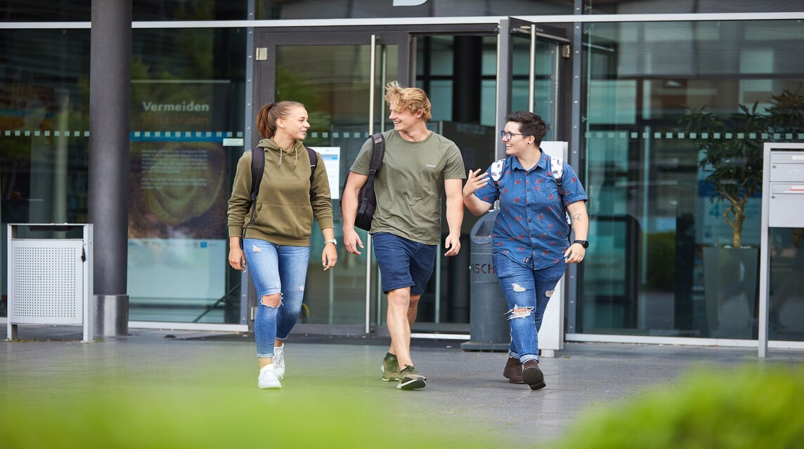 Studierende unterhalten sich laufend am Campus