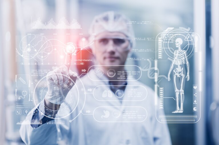 Ein Mann in weißem Medizinerkittel berührt ein transparentes Touch-Pad, auf dem medizinische Zeichnungen zu sehen sind.