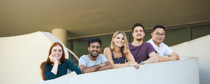 Fünf Personen stehen am Treppenaufgang hinter einer Brüstung.