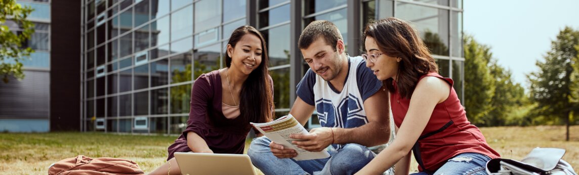 Studierende sitzen im Sommer draußen in der RecreatiionArea des Campus Remagen