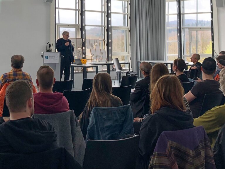 Professor Frietsch auf dem Podium mit Teilnehmenden im Publikum