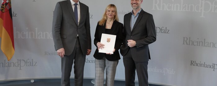 Zwei Männer und eine Frau stehen zusammen.