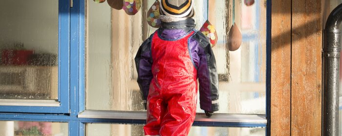 Ein Kind von hinten in Regenkleidung.