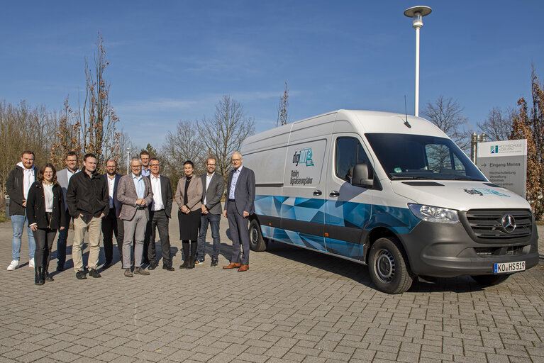 Ein Gruppe von Personen steht vor einem Transporter.