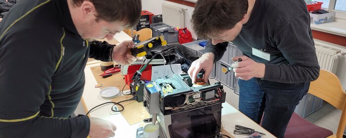 Zwei Männern repaieren Elektrogeräte.