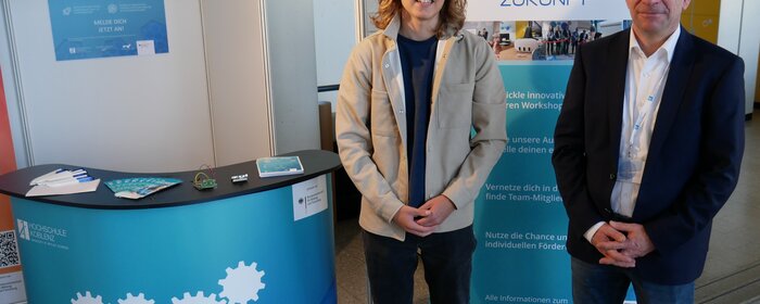 zwei männliche Personen stehen zusammen an einem Projektstand vom StartUpLab