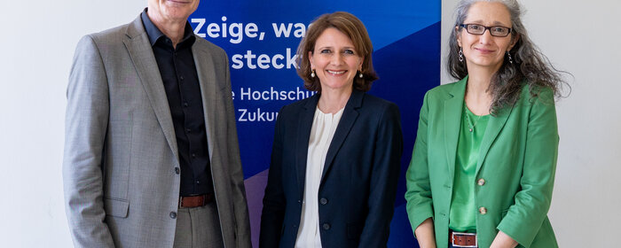 Ein Mann und zwei Frauen stehen vor einer Stellwand mit der Aufschrift "Studieren in Remagen"