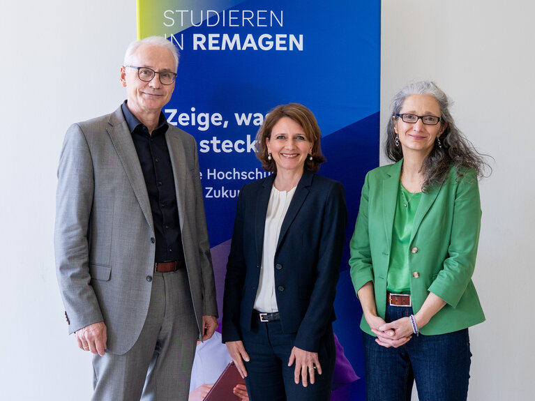 Ein Mann und zwei Frauen stehen vor einer Stellwand mit der Aufschrift "Studieren in Remagen"