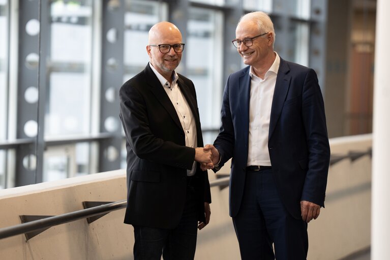 Zwei Männer stehen zusammen und reichen sich die Hand. 