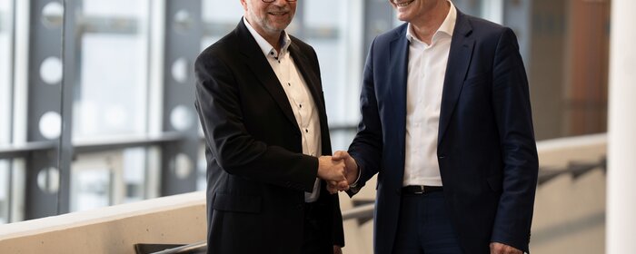 Zwei Männer stehen zusammen und reichen sich die Hand. 