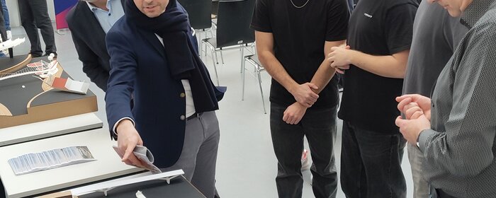 Mehrere Personen stehen um Entwürfe von Architekturstudierenden.