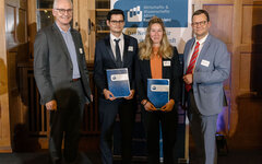 Vier Personen, davon eine Frau und zwei Männer stehen zur Preisverleihung zusammen.