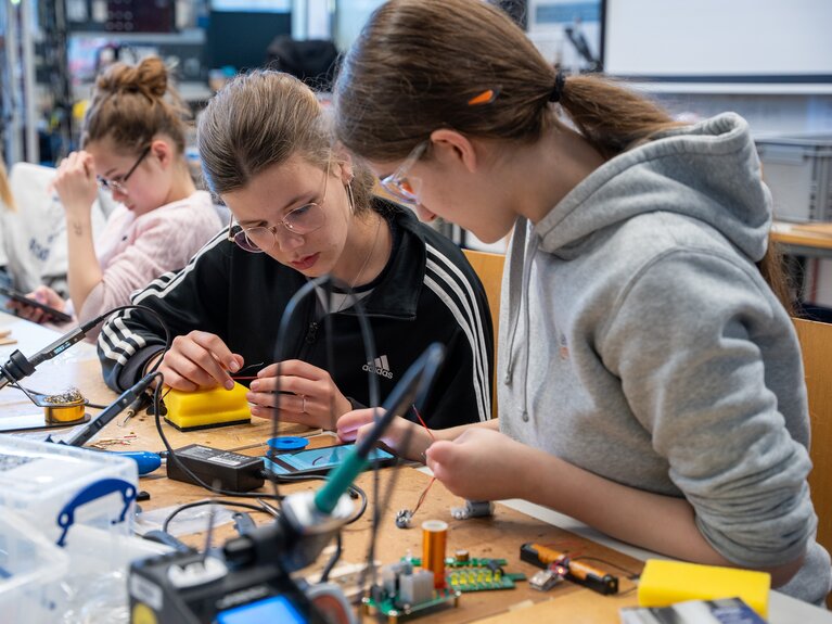 Drei Mädchen sitzen in einem Elektroniklabor.