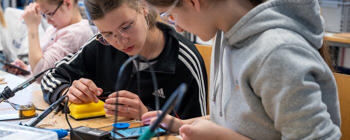 Drei Mädchen sitzen in einem Elektroniklabor.