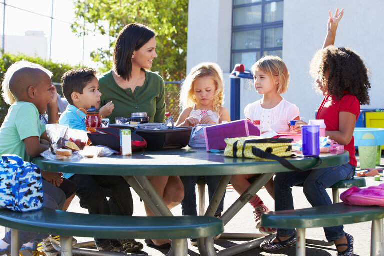 Elementary Pupils And Teacher Eating Lunch