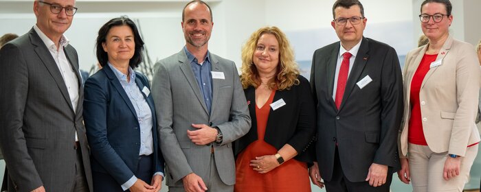 Eine Gruppe von sechs Personen positioniert sich für ein Gruppenfoto.