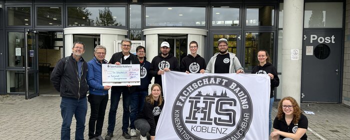Studierende und Vereinsmitarbeitende mit dem Scheck zur Spendenübergabe vor der Hochschule