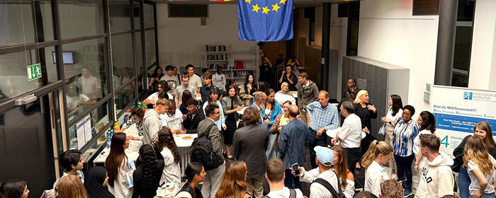 Menschengruppe beim International Day im B-Foyer. Im Hintergrund viele bunte Fahnen