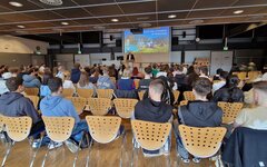 Studierende im Hörsaal von hinten bei der Begrüßung durch den Präsidenten auf der Bühne