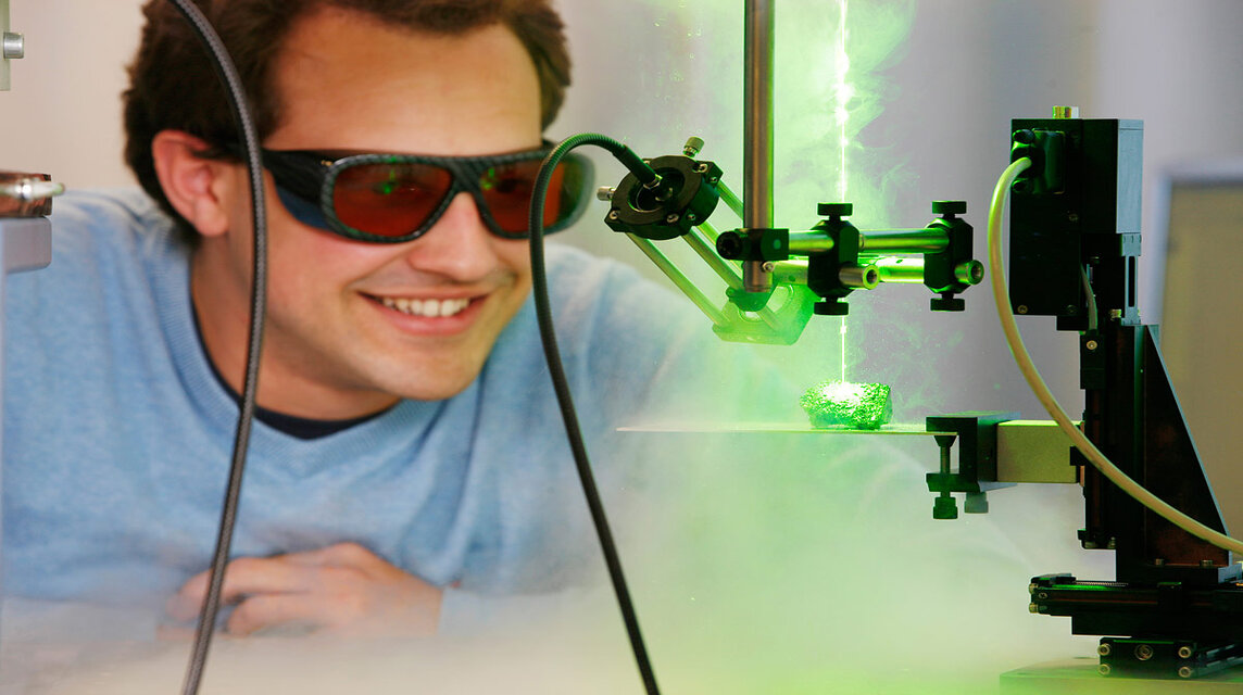 Student mit Schutzbrille vor Laserstrahl