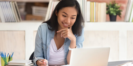 Smiling asian girl student study in library with laptop books