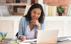 Smiling asian girl student study in library with laptop books