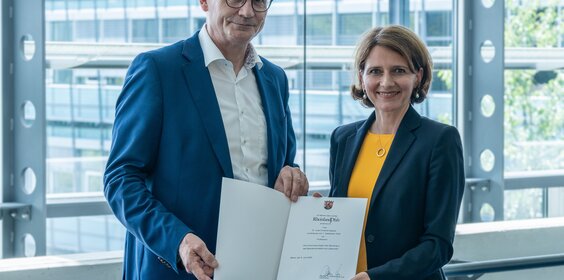 Ein Herr und eine Dame halten eine Urkunde in ihren Händen.
