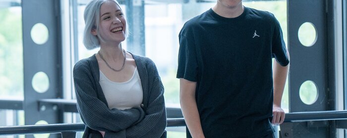 Eine Frau und ein Mann stehen in der Hochschule vor einem Fenster